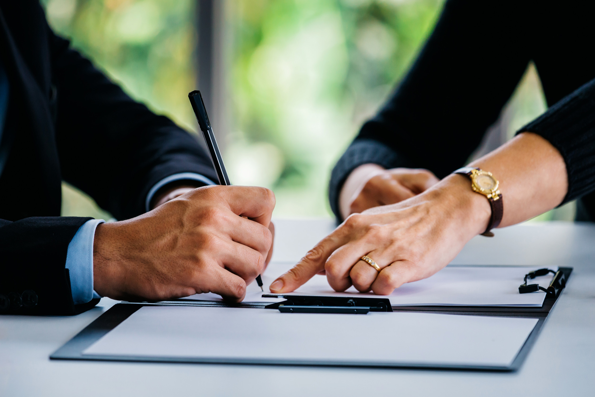 Man signing documents near woman at table